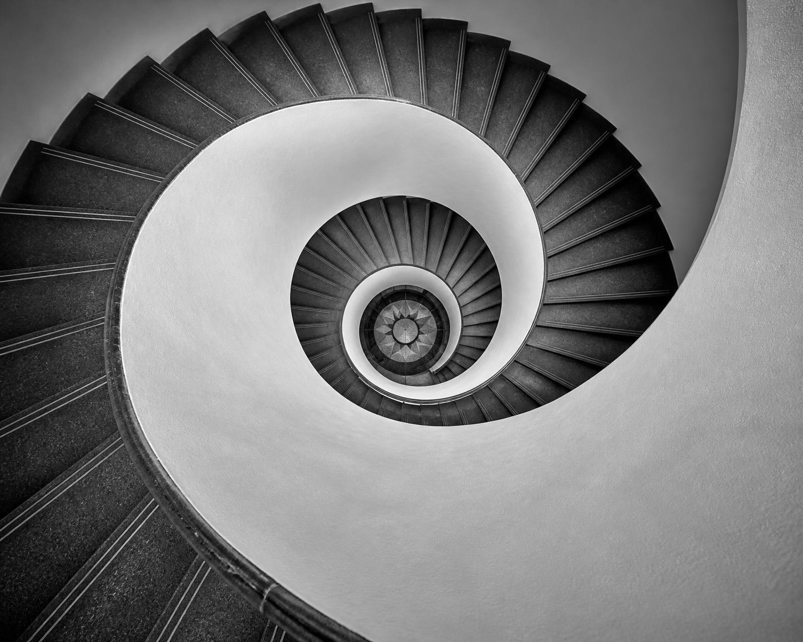 Escadaria em espiral fotografada de cima, alto contraste