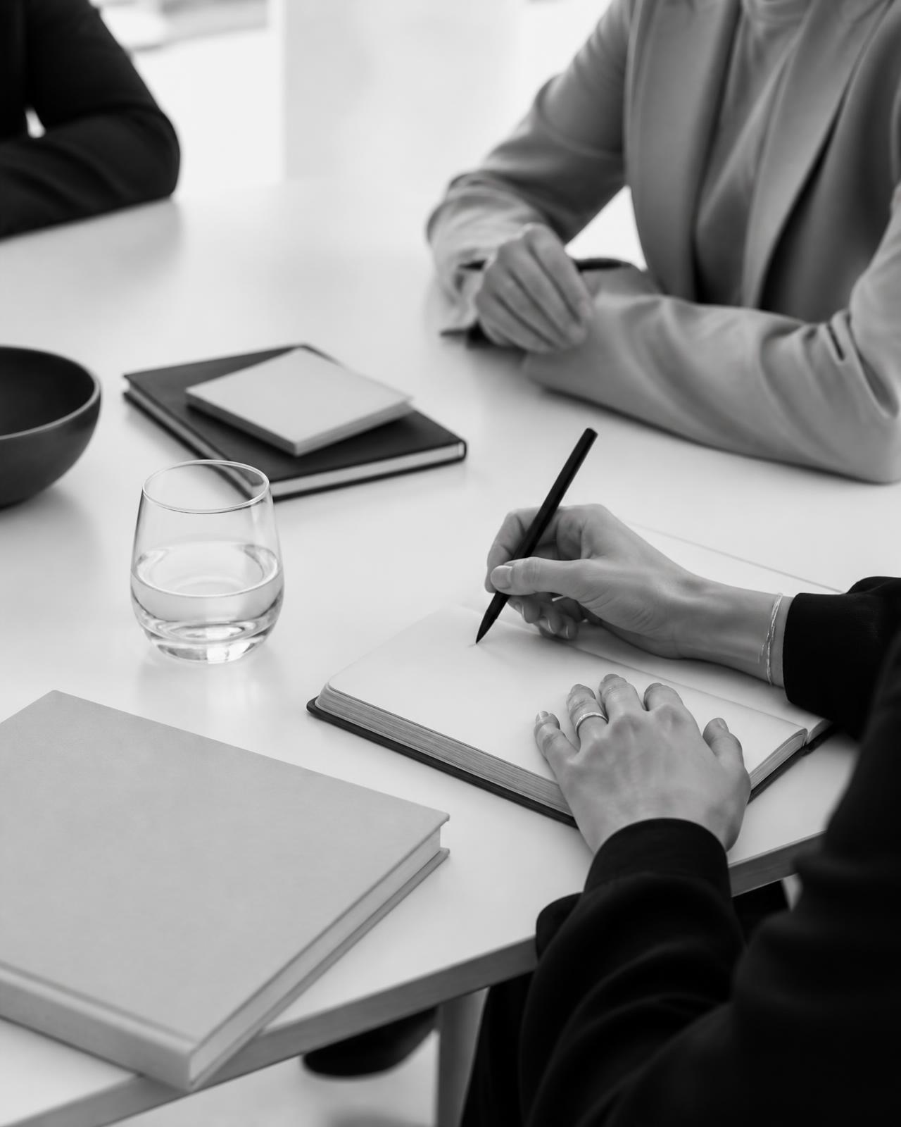 Mãos escrevendo em um caderno sobre a mesa